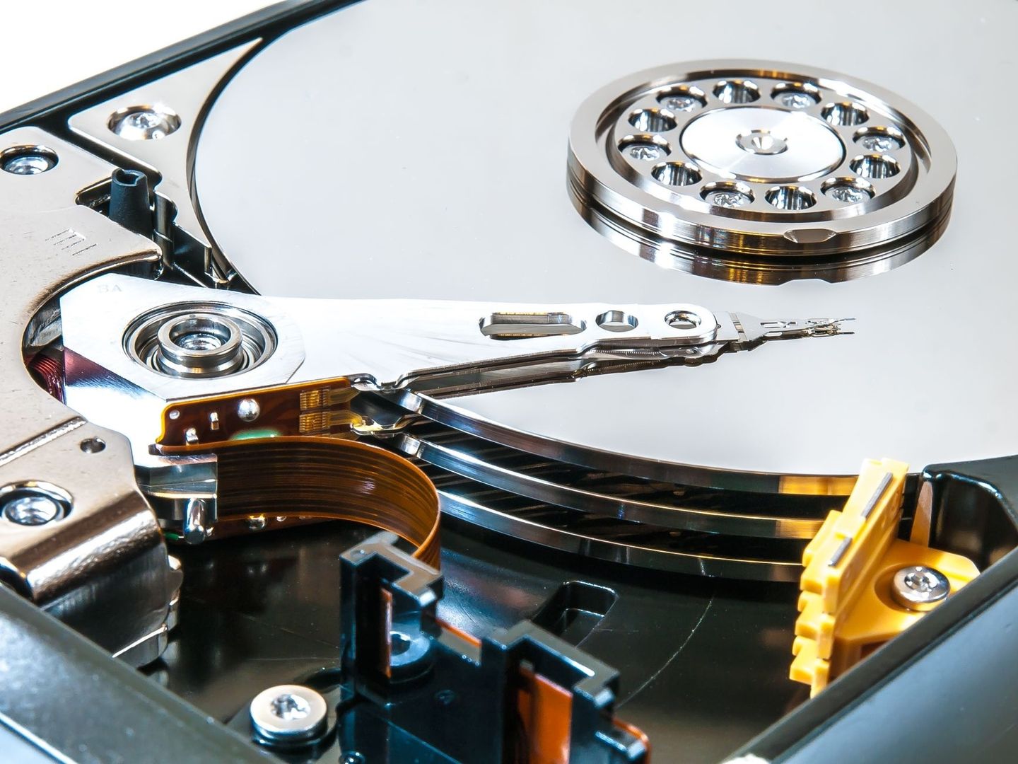 Närbild av en öppnad hårddisk med skiva, läsarm och elektronik